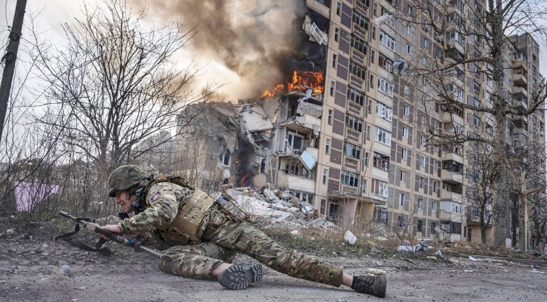 乌克兰士兵站在阿夫迪夫卡一栋被俄罗斯轰炸后起火的建筑前